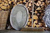 Alter Besen und Metall Tablett auf Holzbank vor geschichtetem Holzlager