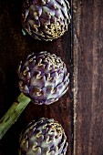 Three artichokes on a wooden surface