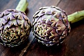 Two artichokes on a wooden surface