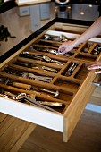 Open wooden cutlery drawer with divisions
