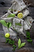 An arrangement of lemons and herbs on a linen cloth on a wooden table