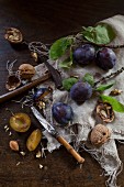 Walnuts and plums with leaves rustic wooden table with a knife and a hammer