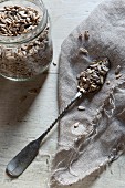 Sunflower seeds on a sliver spoon on a piece of jute
