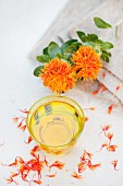 Ein Glas Distelöl aus Färberdistel (Saflor) mit Blüten und Blütenblättern