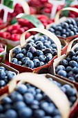 Blueberries and raspberries in cardboard punnets at a market