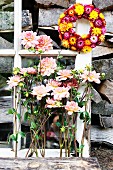 Pink dahlias below wreath of everlasting flowers hanging from lattice window frame