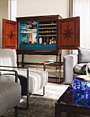 Minibar in antique walnut cabinet in lounge area with pale armchairs