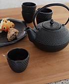 Black, cast iron tea service with Oriental teapot and plate of pastries