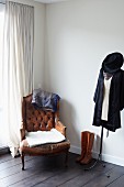 Antique leather armchair, boots and clothing on tailors' dummy in corner