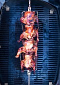 Barbecued chicken on a spit above a grill