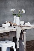 Vase mit Pfingstrosen, Geschirr und Eier auf Holztisch