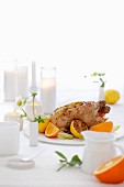 Roast chicken with lemons and oranges on a laid table