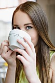 A young woman drinking a large cup of coffee