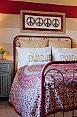 Rotes schmiedeeisernes Bett mit bunter Tagesdecke und Zierkissen