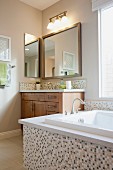 Bathtub, cabinet and mirror in bathroom