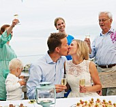Couple kissing and making a toast with group of friends
