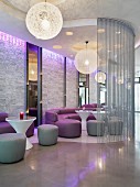 Moderner Lounge-Bereich eines Nachtclubs mit kugelförmigen Deckenleuchten, Ledercouchen & Sitzhockern