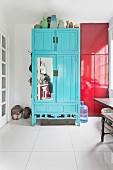 Frau beim Abwasch in der Küche spiegelt sich in Tür eines blauen Schranks