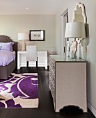 Schlafzimmer in Grautönen mit violetten Farbakzenten, Bett, Schminktisch & silberner Kommode