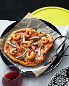 Sliced seafood pizza with white anchovies, prawns, olive oil and dill
