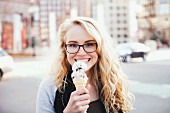 A young blonde woman in town eating an ice cream