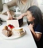 A mother and daughter packing slices of cake into a box