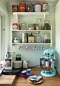 Retro kitchen appliance and espresso machine on worksurface below shelves of storage jars
