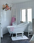 Free-standing vintage bathtub in white bathroom with charcoal grey floor tiles