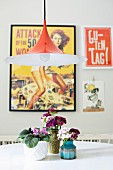 Classic, Danish Semi lamp above retro vases of sweet William and African violets on dining table; vintage posters in background