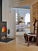 Antique chair in front of wood-burning stove with view through to dining area and Christmas tree in living room