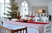 Blick von Esstisch mit rot-weisser, skandinavischer Deko auf geschmückten Weihnachtsbaum