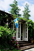 Rustikales Holzhaus mit schwedischer Fahne und Sprossentür