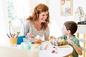 A mother and son dying Easter eggs in a kitchen