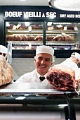 A butcher at a meat counter with dry aged beef