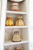 Various lampshades with fabric covers on shelves integrated into long-case clock