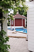 Blick auf Stuhl am Pool mit schwedischem, rot-weißem Gartenhäuschen