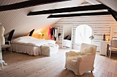 Feminine, white bedroom in converted attic with dark wooden beams