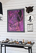 Modern, purple artwork and ornaments above souvenirs on console table