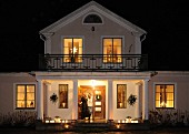Illuminated villa at night with candlelit veranda
