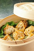 Won tons filled with Thai chicken on a bed of lettuce in a steamer basket