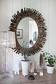 Oval mirror with sunburst metal frame behind Bourgie Lamp by Ferruccio Laviani on surface