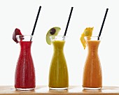 Three different smoothies in carafes