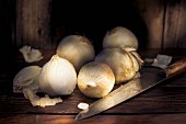 White onions on a wooden table with a knife