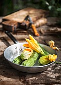 Zucchini und Zucchiniblüten in Metallpfanne