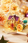 Weihnachtsdeko mit Rosenblüten & Baumanhänger in Hausform auf Sternenteller