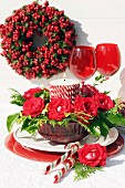 Festive arrangement in red with roses & candle in glass bowl