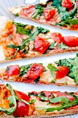 Slices of pizza topped with fresh rocket and cherry tomatoes