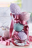Easter arrangement of ceramic eggs with various lacy patterns and satin ribbon in glass vase