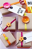 Gift boxes with brown paper lids decorated with buttons, ribbons & tags