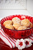 Mini doughnuts in a red glass bowl on a red and white stripped napkin